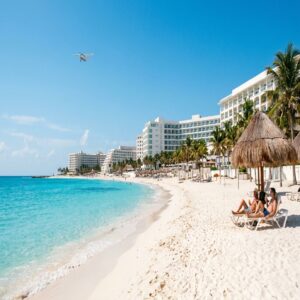 Praia de Cancún com mar turquesa, resorts all-inclusive e turistas relaxando na areia