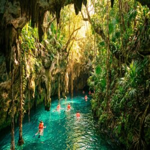 Rio subterrâneo do parque Xcaret com pessoas fazendo snorkel