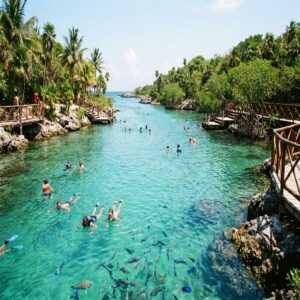 Enseada turquesa do parque Xel-Há com pessoas fazendo snorkel