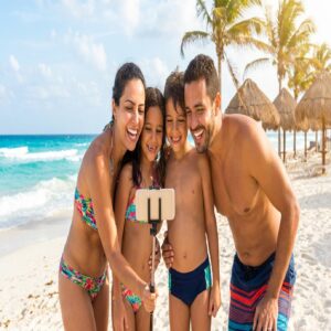 Família brasileira feliz na praia de Cancún consultando o celular